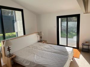 una camera con un letto e due grandi finestre di Maison en bord de rivière de mer a Le Fenouiller