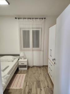 Habitación blanca con cama y ventana en H&D Apartment en Sumartin