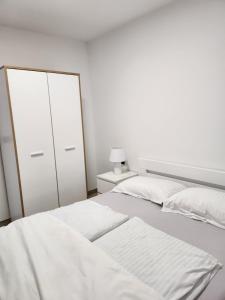 a white bedroom with a bed and a dresser at H&D Apartment in Sumartin