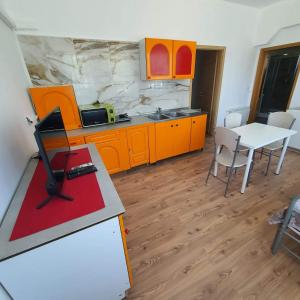 una cocina con armarios naranjas y una mesa blanca en Apartments Garden en Koper