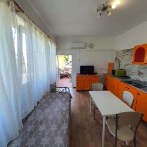 a kitchen with orange cabinets and a table in a room at Apartments Garden in Koper