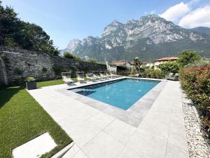 a swimming pool with chairs and a mountain in the background at Residence Zangirolami - Luxury Garden and Balcony Apartments in Riva del Garda