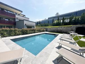 a swimming pool with lounge chairs next to a building at Residence Zangirolami - Luxury Garden and Balcony Apartments in Riva del Garda