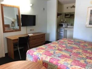 Habitación de hotel con cama, escritorio y espejo. en Flamingo Inn, en Kissimmee