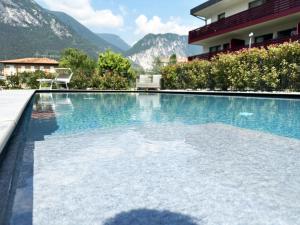 a swimming pool in front of a building with mountains at Residence Zangirolami - Luxury Garden and Balcony Apartments in Riva del Garda