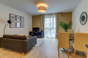 ein Wohnzimmer mit einem Sofa und einem Tisch in der Unterkunft OVELIA Dijon - Le Courtille Ste-Marthe in Dijon