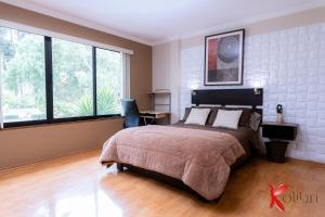 1 dormitorio con 1 cama grande y ventanas grandes en Hostal Kolibri B&B, en Cuenca