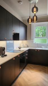 a kitchen with black cabinets and a sink and a window at Contemporary beach apartment in Brighton & Hove