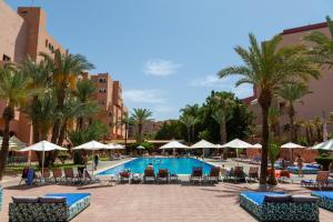 a resort pool with chairs and umbrellas and palm trees at Rose Aqua Park Hotel in Marrakesh
