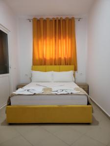 - un lit jaune dans une chambre avec un rideau orange dans l'établissement Hostel K13, à Saranda