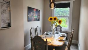 a dining room table with a vase of sunflowers on it at Contemporary beach apartment in Brighton & Hove