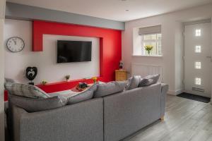 a living room with a couch and a red wall at NEW Luxurious Escape Charming Dog Friendly Cottage in Caernarfon