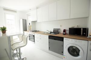 a kitchen with white cabinets and a washer and dryer at 3 Rooms A502 StayInn by Cosmopolis in Bucharest
