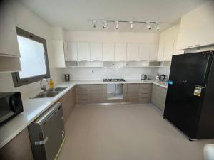 a kitchen with white cabinets and a black refrigerator at MKD Marina Residence in El Alamein +8 photos