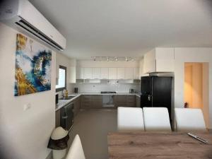a kitchen with white cabinets and a black refrigerator at MKD Marina Residence in El Alamein