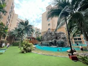 a pool in a resort with palm trees and people in it at Atlantis condo G bless in Jomtien Beach