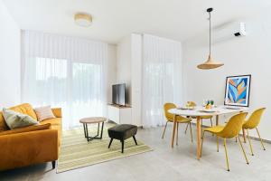 a living room with a table and yellow chairs at Apartments San Maris 2 in Umag