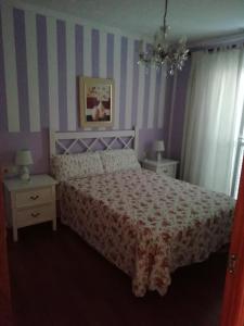Dormitorio con cama con pared de rayas rosa y morada en Apartamento en Duplex, en Jerez de la Frontera