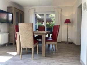 a dining room with a wooden table and red chairs at Kellenhusen - Ferienhaus Gabi in Kellenhusen
