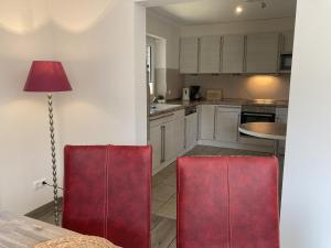 a kitchen with a table and two red chairs at Kellenhusen - Ferienhaus Gabi in Kellenhusen +24 photos