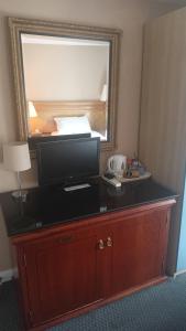 a desk with a television and a mirror in a hotel room at Hotel Sergul in London