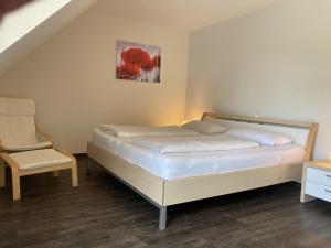 a bedroom with a bed and a chair in a room at Kellenhusen - Ferienhaus Gabi in Kellenhusen