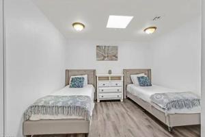 two beds in a bedroom with white walls and wooden floors at Beautiful Oasis with rv or boat parking in Las Vegas