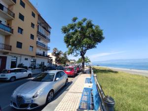 rząd samochodów zaparkowanych na chodniku obok plaży w obiekcie Casa Vacanza dai Compari w mieście Ali Terme