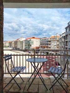 d'une table et de chaises sur un balcon avec vue sur la ville. dans l'établissement Desconectaengalicia San Isidro, a pie de playa Silgar, à Sanxenxo