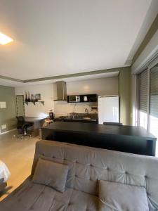 a living room with a couch and a kitchen at Sem Taxas! Studio Central, Moderno e C/ Garagem in Pelotas