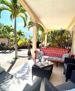 a red couch on a patio with palm trees at Villa Ti MoOn, Entre deux, Piscine in LʼEntre-Deux