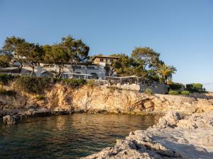 a house on top of a cliff next to the water at Hotel Bendinat in Portals Nous