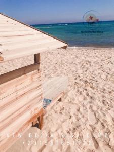 a wooden building on a sandy beach next to the ocean at New Bella Sina Camp in Nuweiba