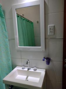 a bathroom sink with a mirror and a green shower curtain at La casita de Isa in Gualeguay