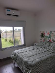 1 dormitorio con cama y ventana grande en La casita de Isa en Gualeguay