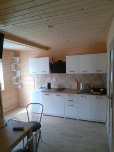 a kitchen with white cabinets and a wooden ceiling at Domki Bieszczady Całoroczne in Olszanica