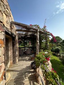 a stone building with a wooden walkway with flowers at Hôtel Ambassador Palombaggia in Porto-Vecchio