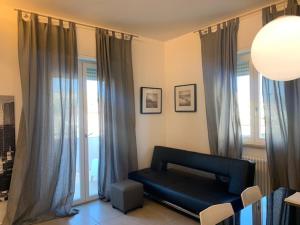 a living room with a black couch in front of windows at Residence La Nave in Senigallia