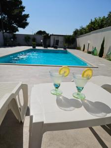 un tavolo bianco con due bicchieri di vino sopra accanto a una piscina di Villa Giulia a Marinella di Selinunte