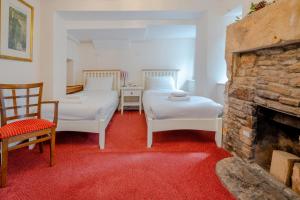 two beds in a room with a fireplace at Crown Hotel Cotswold in Blockley