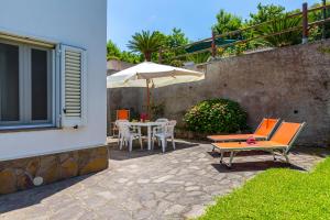 een patio met een parasol en een tafel en stoelen bij Le Castagne Apartments Ischia in Ischia