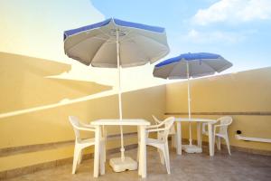 two tables and chairs with umbrellas on a patio at Duci Duci Appartamenti in Trapani