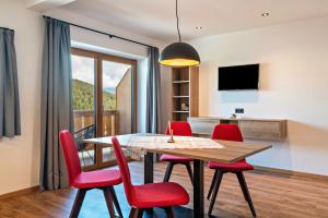 a dining room with a table and red chairs at Morodeserhof Apt Bühlen 2 in Castelrotto