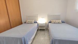 2 łóżka w małym pokoju z szafką nocną w obiekcie TurAlmeria - Mirador Del Cabo1 - Apartamento con 2 dormitorios, 2 baños, piscina y plaza de garaje con vistas al mar en Retamar - Almería w mieście Retamar