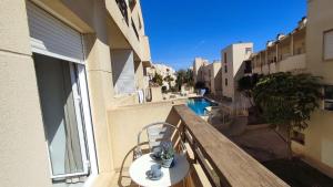 balkon ze stołem i krzesłami oraz basenem w obiekcie TurAlmeria - Mirador Del Cabo1 - Apartamento con 2 dormitorios, 2 baños, piscina y plaza de garaje con vistas al mar en Retamar - Almería w mieście Retamar