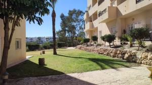 dziedziniec budynku z palmami i chodnikiem w obiekcie TurAlmeria - Mirador Del Cabo1 - Apartamento con 2 dormitorios, 2 baños, piscina y plaza de garaje con vistas al mar en Retamar - Almería w mieście Retamar