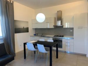 eine Küche mit einem schwarzen Tisch und weißen Stühlen in der Unterkunft Residence La Nave in Senigallia