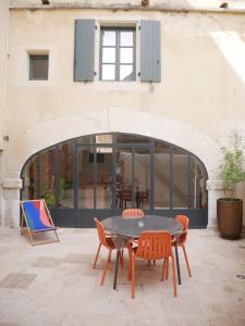 un patio con mesa y sillas frente a un edificio en Le Clos des Confidences en Grignan