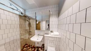 a white tiled bathroom with a sink and a mirror at Second Home Apartments Asplund in Solna +36 photos