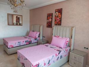 twee bedden in een kamer met roze lakens bij Residence La corniche Étage 2 in Nador